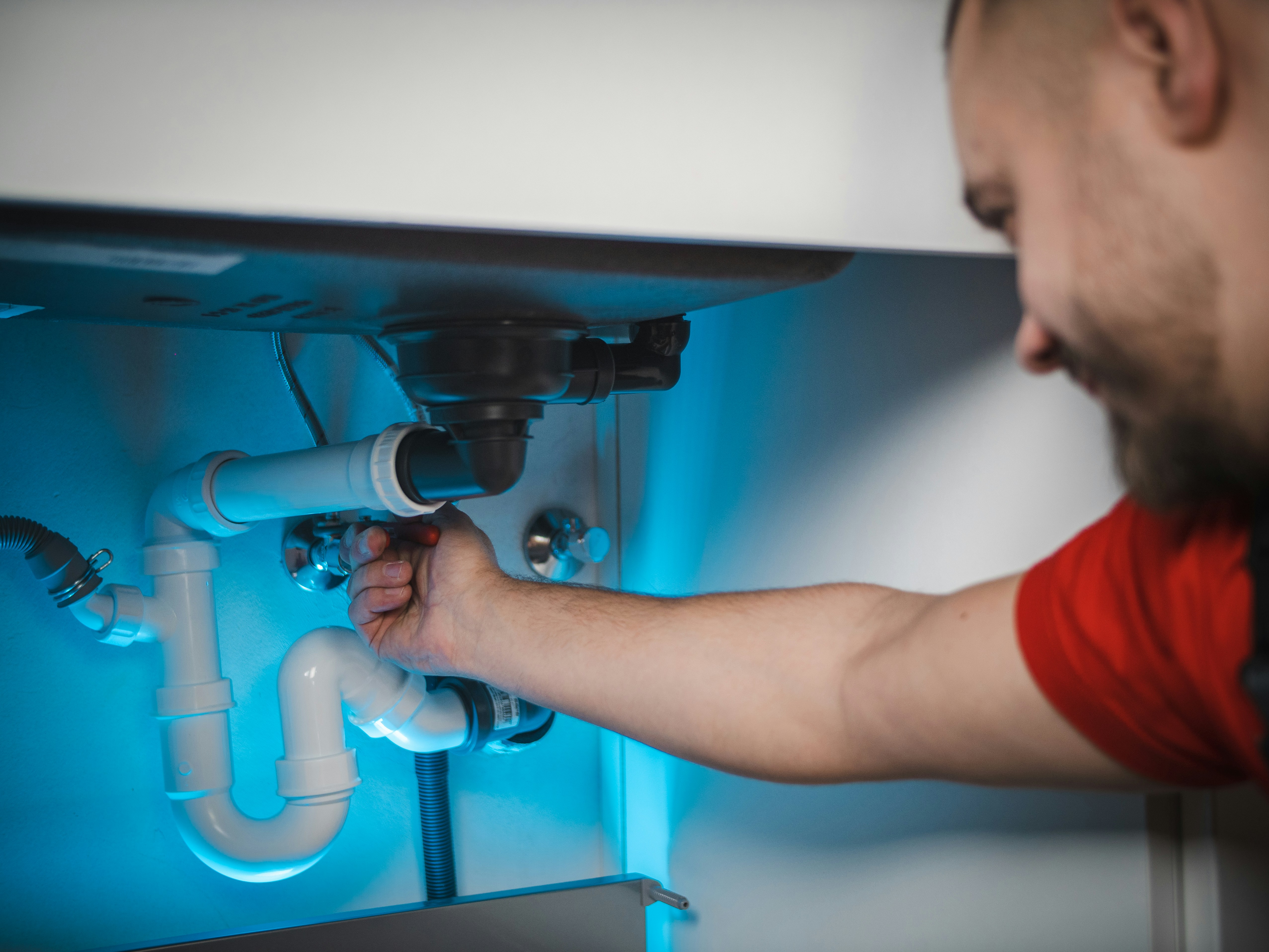 Plumber repairing sink trap under kitchen cabinet